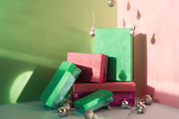 Pastel pink and green mint silver box set for Christmas gift, standing upright and decorative toy balls flying around. Funny warmth tones composition. Happy holiday layout. New year neo preparation