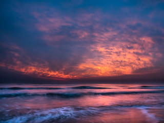 Naklejka na ściany i meble Beautiful orange dawn / sunrise over the Mediterranean Sea, waves splashing against the shore