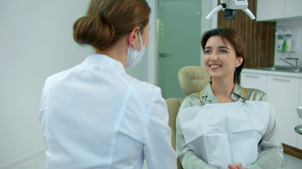 Fototapeta premium Smiling girl talks to doctor in clinic