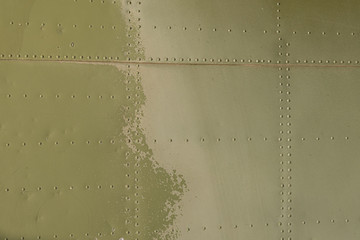 Old green metal surface of the aircraft fuselage with rivets