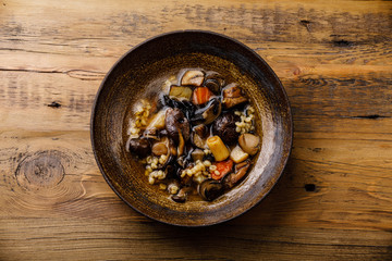 Healing Soup with roots, mushrooms and barley on wooden table background