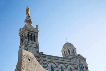 Beautiful view of Notre Dame de la Garde in Marseille against a bright blue sky on a sunny day.