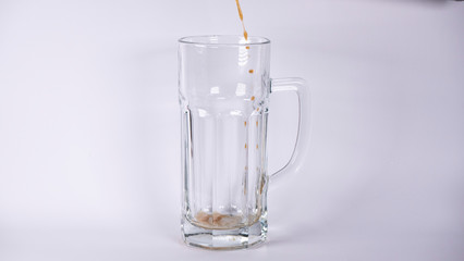 Pour beer into a glass with dark beer and foam on a white background