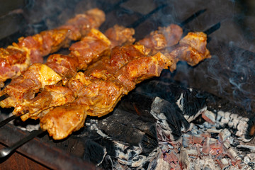 Roasted meat on skewers is cooked over burning coals.