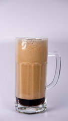 Beer glass with dark beer and foam on a white background