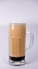 Beer glass with dark beer and foam on a white background