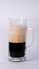Beer glass with dark beer and foam on a white background