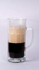 Beer glass with dark beer and foam on a white background