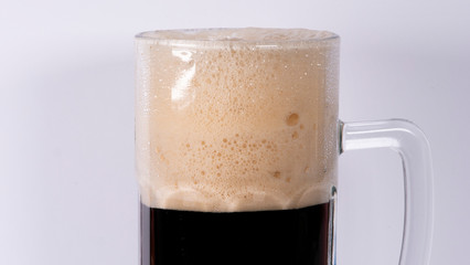 Beer glass with dark beer and foam on a white background