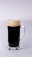Beer glass with dark beer and foam on a white background