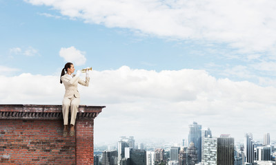 Beautiful young woman playing trumpet on roof