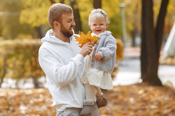 Family in a autumn park. Woman in a brown sweater. Cute newborn little girl with parents