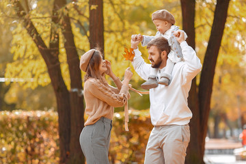 Family in a autumn park. Woman in a brown sweater. Cute newborn little girl with parents