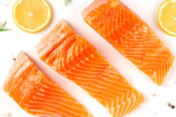 Slices of salmon with lemon, a flat lay close-up top-down shot with salt and pepper, cooking fish, on a white background