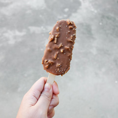 Hands holding vanilla icecreams covered with chocolate and almonds