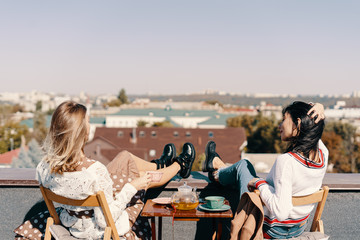Two attractive girls enjoy a tea party on the rooftop overlooking the city