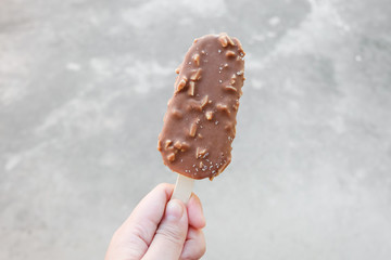 Hands holding vanilla icecreams covered with chocolate and almonds