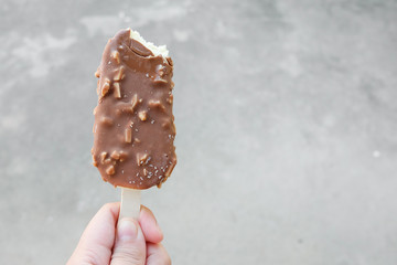 Hands holding vanilla icecreams covered with chocolate and almonds