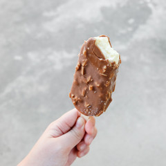 Hands holding vanilla icecreams covered with chocolate and almonds