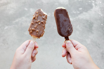 Hands holding vanilla icecreams covered with chocolate and almonds