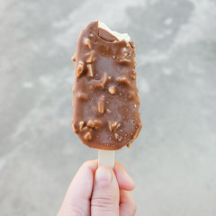 Hands holding vanilla icecreams covered with chocolate and almonds
