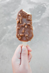 Hands holding vanilla icecreams covered with chocolate and almonds