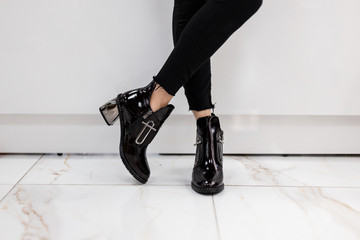 Fashionable young woman in stylish black jeans in trendy patent leather shoes with silver heel...