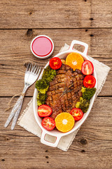 Baked duck breast on the bone with vegetables and sauce. Traditional healthy food concept. Vintage wooden boards background