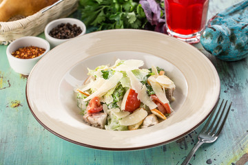 Healthy Grilled Chicken Caesar Salad with parmesan Cheese and Croutons on blue wooden table