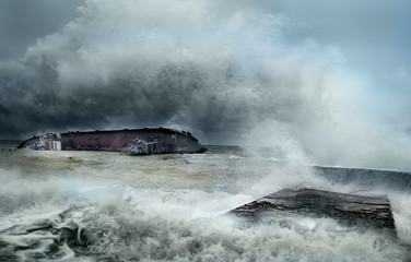 A sunken old ship with a tanker on its side stranded on the seashore amidst giant waves. dramatic sky and stormy sea. Odessa. Ukraine. Black Sea