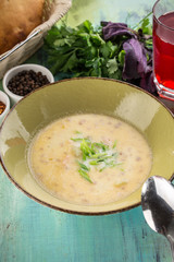 homemade vegetable soup with green onion in green bowl on blue wooden table