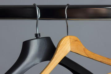 Perchas de la ropa colgadas de un perchero. Percha de plástico y percha de maderas, vacías de ropa