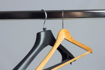 Perchas de la ropa colgadas de un perchero. Percha de plástico y percha de maderas, vacías de ropa