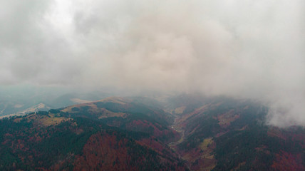 Fototapeta premium View from a drone to a glade and autumn forest through the fog in the Carpathian mountains.