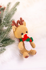 Crochet Christmas deer and Christmas tree fir on a light background. Vertical orientation