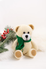 Crocheted toy bear in a green scarf on a light background