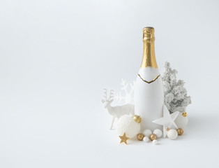 Christmas or New Year party layout with white champagne bottle and golden Christmas decoration. Bright  Holiday party background. © Zamurovic Brothers