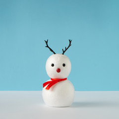 Snowman on bright blue background with reindeer nose and antlers. Winter holiday concept. Christmas...