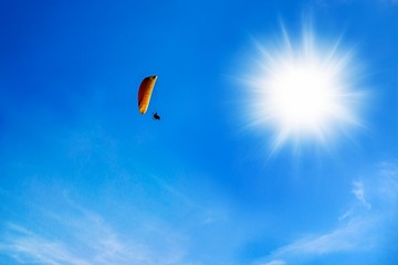  Paraglider is flying over the high mountains. Paragliding on beautiful sky background
