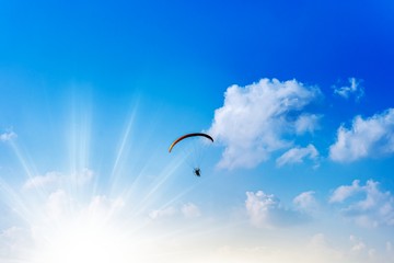  Paraglider is flying over the high mountains. Paragliding on beautiful sky background