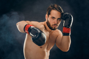 Fototapeta na wymiar shirtless boxer with gloves on dark background in smoke