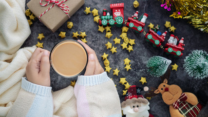 hand holding hot drink in winter season with Christmas background decorations and gift boxes on table