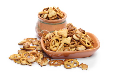 Salty cracker and pretzel snacks, party mix in clay bowl, pot isolated on white background