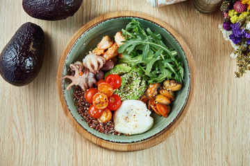 Seafood bowl with avocado, quinoa, octopus, mussels, cherry tomatoes and poached egg. Buddha bowl with healthy and balanced food. Top view, flat lay