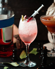 fizzy drink in glass with red sauce garnished with dried rose petal
