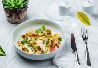 bowl of dumplings with parmesan, arugula and tomato