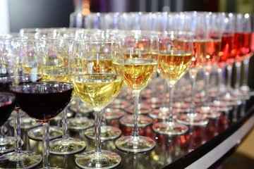 Rows of full champagne, sparkling wine and red wine glasses. Dining, drink. Catering service concept.