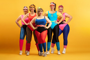 Fototapeta premium Young caucasian plus size female models training on yellow background. Copyspace. Concept of sport, healthy lifestyle, body positive, fashion. Friendship, girl power. Stylish woman posing, smiling.