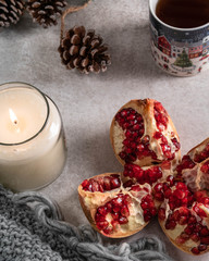 pomegranate and candle, on a light marble backdrop, cup of tea and Christmas ornament on background