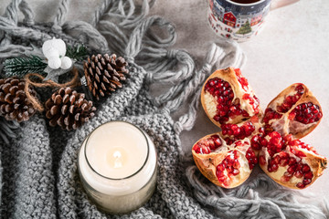 pomegranate and candle, on a light marble backdrop, cup of tea and Christmas ornament on background